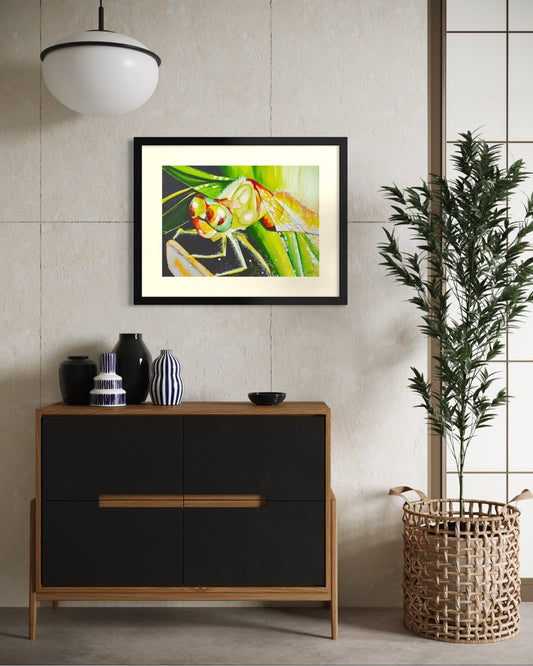 Black framed A2 dragonfly painting in a Japandi room with a concrete tile wall, oak chest, dark vases, woven basket and an olive tree.