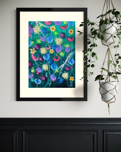Black framed A2 wildflower art print on a soft white wall above black panelled wainscoting beside two macrame hanging pothos planters.