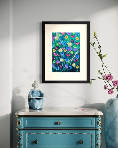 Black framed A3 wildflower art print on a soft white wall above a blue painted Louis chest with a marble top and a blue ceramic figurine.