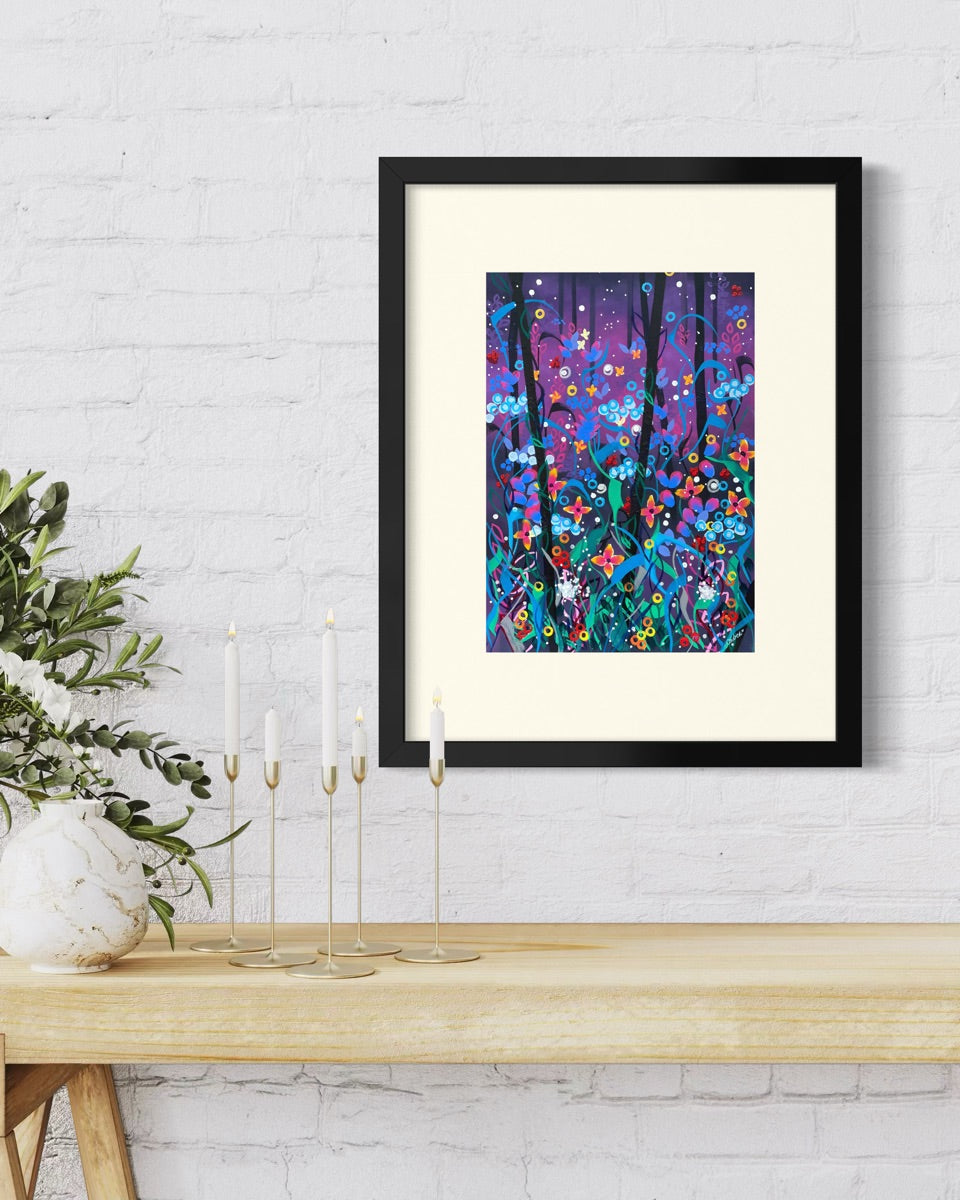 Black framed A4 wildflower art print on a whitewashed brick wall above a pine bench with eucalyptus in a stone vase and slim brass candlesticks.