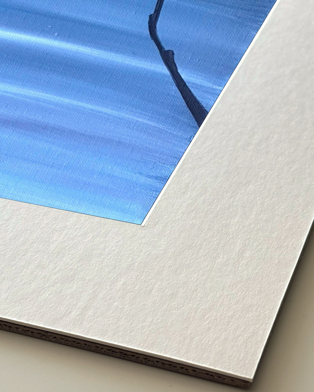 Andrea Nicole 'Patience' giclée fine art print in an off-white window mount, shown corner-on so the bevel-cut window opening, 100% cotton paper and mount board are visible. | an:family=print;role=mount